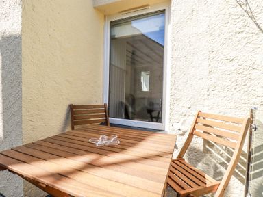 A wooden table with two wooden chairs on a small outdoor patio at Hilldene in Treknow