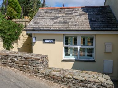 An exterior view of a house with a sign and stone wall at Hilldene in Treknow