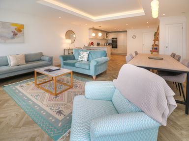 An open plan living room and kitchen with sofas and a dining table at Ameila's Point in St Ives
