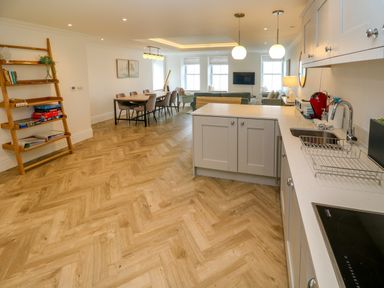 An open plan kitchen and dining area with wooden flooring and a wooden bookshelf at Amelia's Point in St Ives