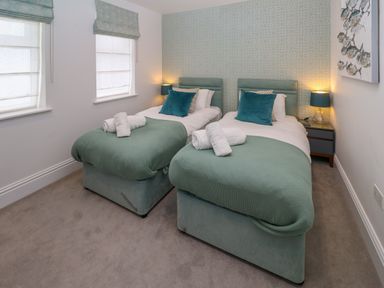 A bedroom with two single beds and teal bedding at Amelias Point in St Ives