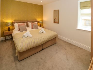 A bedroom with a double bed bedside tables with lamps a window and a framed picture at Amelia's Point in St Ives