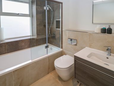 A bathroom with a bathtub and shower combination next to a toilet and sink at Amelia's Point in St Ives