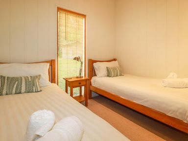 A bedroom with two single beds a wooden nightstand a desk lamp and rolled towels at 10 Water's Edge Lanreath