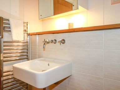 A bathroom sink with wall-mounted faucet and towel rack with a towel at 10 Water's Edge in Lanreath