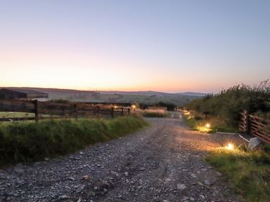 A gravel road with small lights along the sides and wooden fences on both sides at Rhosydd in Cyffylliog near Ruthin