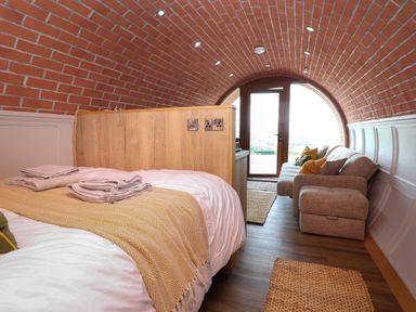 A bedroom with a bed folded towels and a sofa under an arched brick ceiling at Cae Bach in Cyffylliog near Ruthin