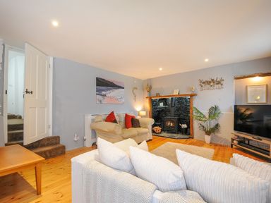 A living room with sofas a wood stove a television and a wooden table at Stone's Throw Cottage in Launceston