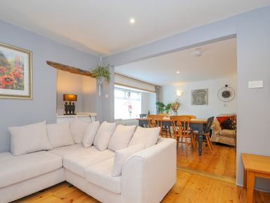 A living room with a white sectional sofa and wooden dining table with chairs at Stone's Throw Cottage in Launceston
