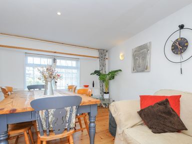 A dining area with a wooden table and mixed chairs next to a seating area with cushions at Stone's Throw Cottage in Launceston