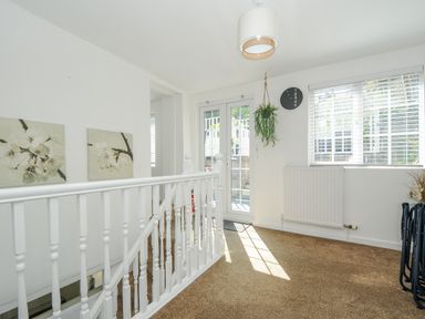 A hallway with white railing two floral paintings and a hanging plant at Stones Throw Cottage in Launceston