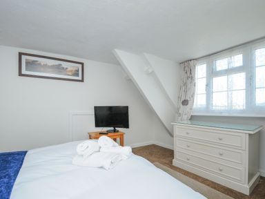 A bedroom with a bed white dresser small table and television at Stones Throw Cottage in Launceston