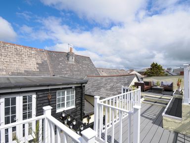 An outdoor rooftop deck with white railings black wooden siding and outdoor seating area at Stone's Throw Cottage in Launceston
