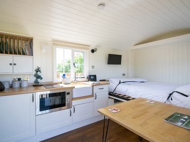 A compact kitchen and sleeping area with a bed a microwave a sink and a table at Strathmore in Burnside near Forfar