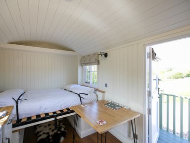 A small room with a single bed a wooden table an open door and a window at Strathmore in Burnside near Forfar