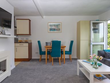 A dining room with a wooden table and teal chairs and a living area with a white coffee table and a gray sofa at Florences Nest in Dartmouth
