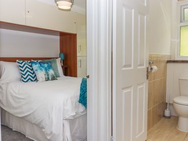 A bedroom with a bed and pillows next to a bathroom with a toilet at Florences Nest in Dartmouth