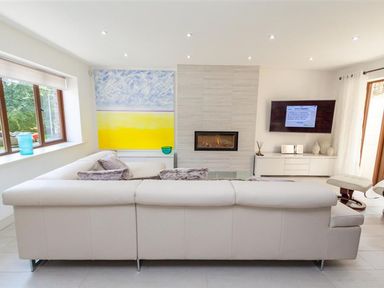 A living room with a white sectional sofa a wall-mounted television and a fireplace at The Arthouse in Ambleside