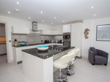 A kitchen with an island and two chairs next to a grey armchair at The Arthouse in Ambleside