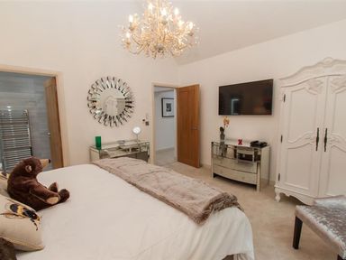 A bedroom with a bed a mirror a chandelier a white wardrobe and a television at The Arthouse in Ambleside