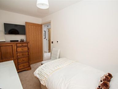 A bedroom with a single bed a white chair a wooden dresser and a wall-mounted TV at The Arthouse in Ambleside
