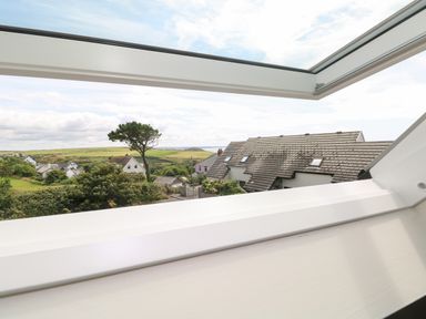 A view through a skylight window showing rooftops trees and fields at Carreg Ddu in Solva