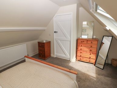 A bedroom with a bed a small chest of drawers a larger dresser with a mirror and a full-length mirror at Carreg Ddu in Solva