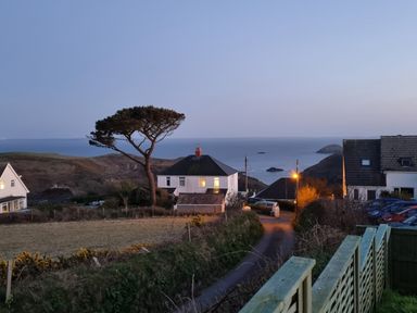 A coastal view with houses a tree a road and the sea in the background at Carreg Ddu in Solva