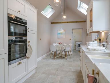 A kitchen with double ovens a round dining table with chairs and skylights at West View in Feltwell