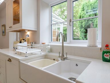 A kitchen sink area with a faucet a dish drying rack soap dispenser paper towels and a window looking outside at West View in Feltwell