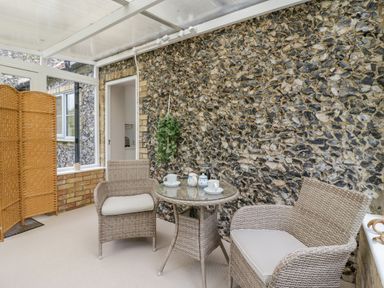 A conservatory with wicker chairs and a round glass table with teacups at West View in Feltwell