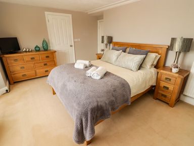 A bedroom with a wooden bed and dresser with towels on the bed at Morva in New Quay