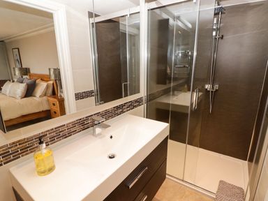 A bathroom with a sink and a shower enclosure with glass doors and a view of a bedroom at Morva in New Quay