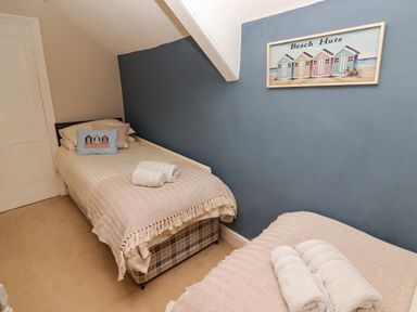 A bedroom with two single beds covered with beige blankets and towels on them at Morva in New Quay