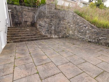 A stone-paved outdoor patio with steps leading to a small table and two chairs surrounded by stone walls at Morva in New Quay