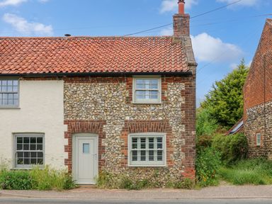 A cottage with a red tiled roof and pebble dash walls with white door and windows at Daisys Place in South Creake near Little Walsingham