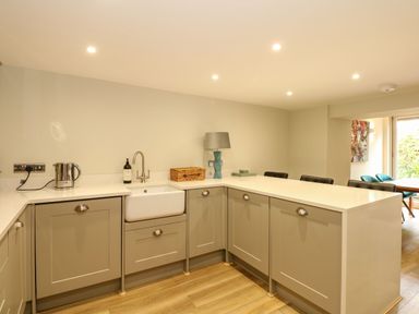A kitchen with beige cabinets a white countertop a sink kettle and a lamp at Daisys Place South Creake near Little Walsingham