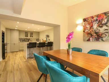 A kitchen and dining area with wooden dining table and teal chairs at Daisy's Place in South Creake near Little Walsingham