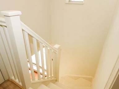 An indoor staircase with white banisters and handrails with beige walls at Daisys Place in South Creake near Little Walsingham