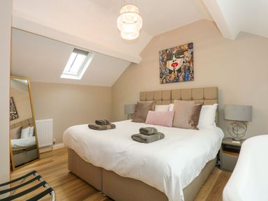 A bedroom with a bed with pillows and towels a floor mirror skylight and a bedside table with a lamp at Daisys Place in South Creake near Little Walsingham