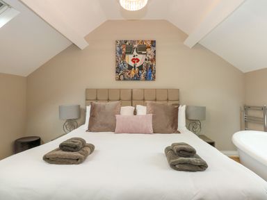 A bedroom with a bed pillows towels lamps and a painting above the headboard at Daisys Place in South Creake near Little Walsingham