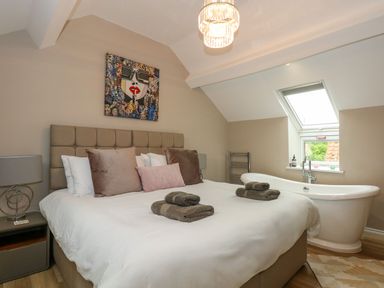 A bedroom with a large bed pillows folded towels a bathtub and a skylight window at Daisys Place in South Creake near Little Walsingham