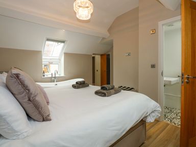 A bedroom with a bed pillows and towels near a window and a bathtub at Daisys Place South Creake near Little Walsingham