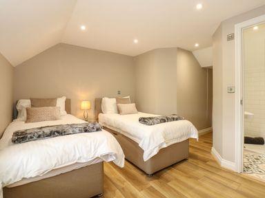 A bedroom with two single beds a lamp and an ensuite bathroom at Daisys Place in South Creake near Little Walsingham