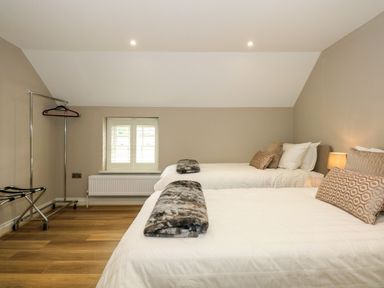 A bedroom with two beds brown and white bedding a window and clothes rack at Daisys Place in South Creake near Little Walsingham