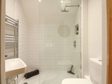 A bathroom with a walk in shower a white sink a toilet and a towel rack at Daisys Place South Creake near Little Walsingham