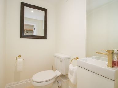 A bathroom with a toilet sink mirror and towel at Daniels Farmhouse in Claines