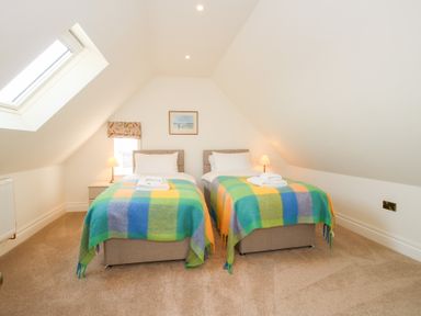 A bedroom with two single beds and colorful blankets under a sloped ceiling at Daniels Farmhouse in Claines