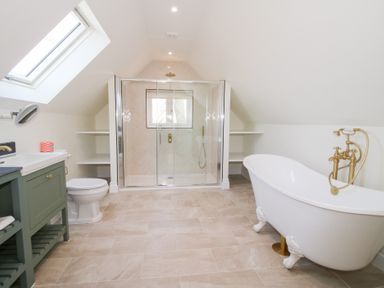 A bathroom with a green vanity unit toilet freestanding bathtub and glass shower at Daniels Farmhouse in Claines