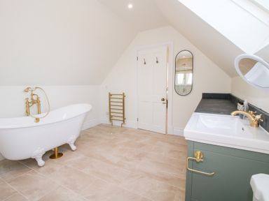 A bathroom with a clawfoot bathtub sink cabinet towel rack and mirror at Daniels Farmhouse in Claines